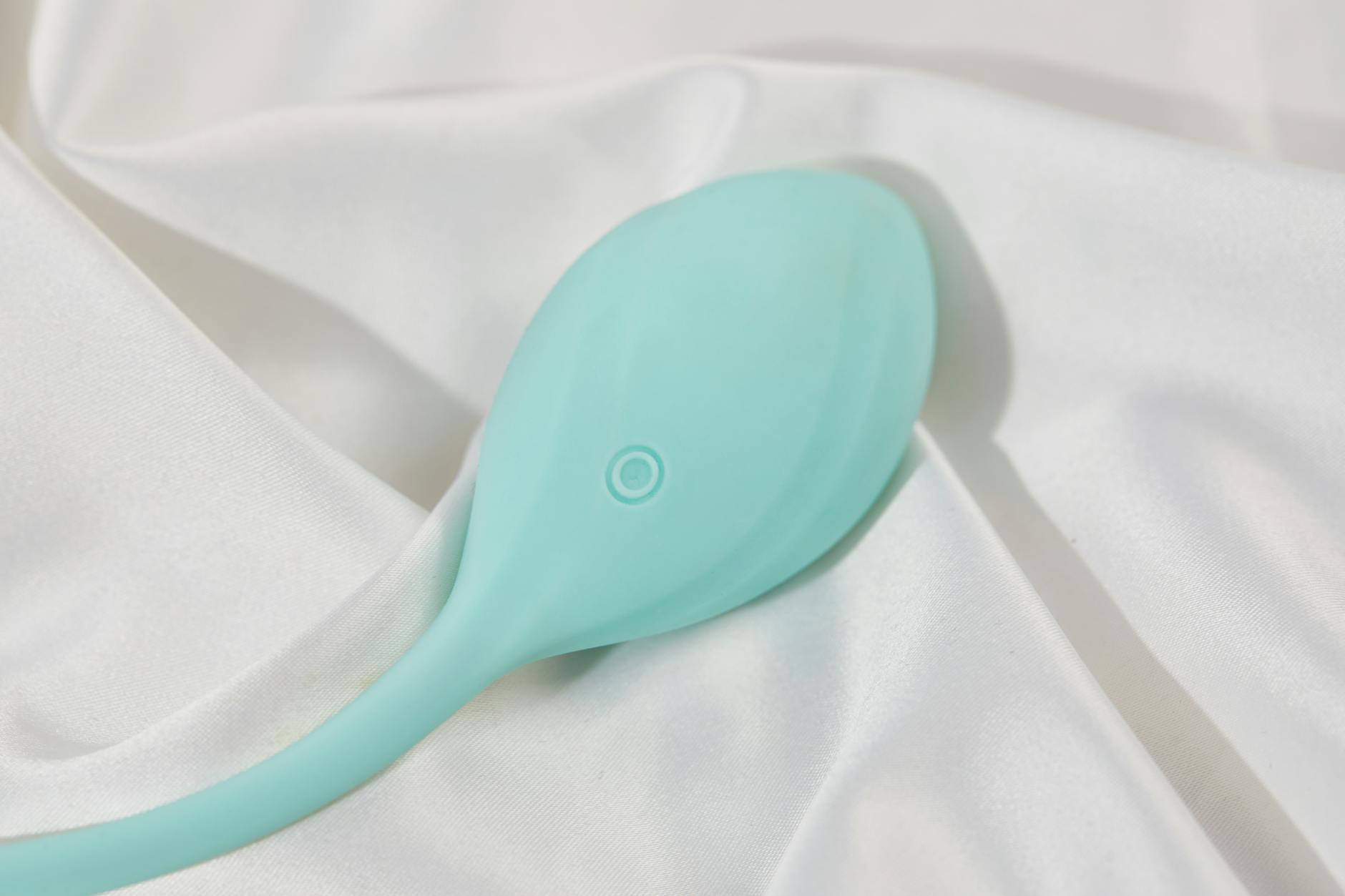A sleek teal lemon clitoral sucker on white silk, representing the transition from traditional vibrators to modern suction technology