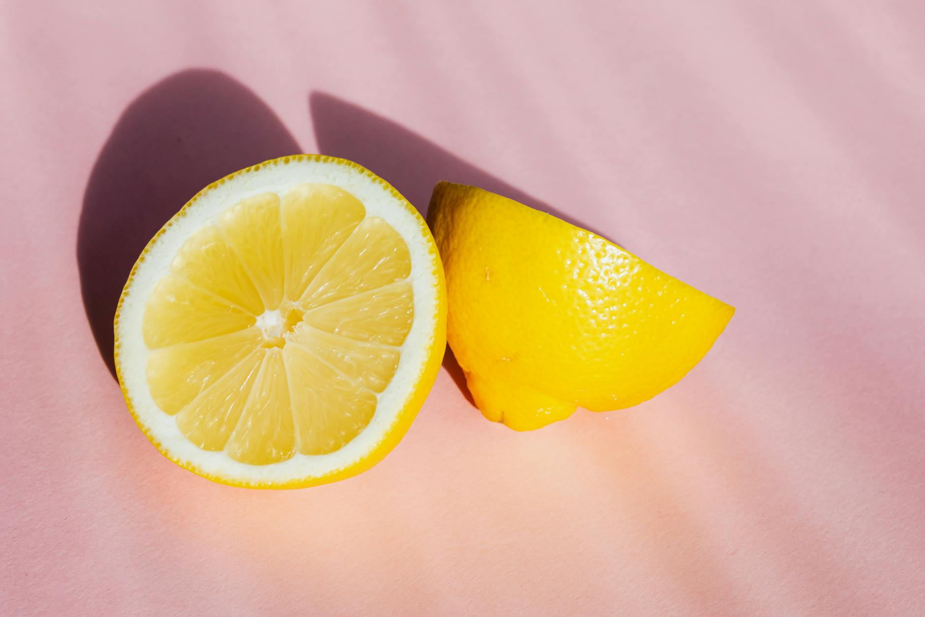 Fresh lemon halves on pink background symbolizing medication side effects and vaginal dryness solutions
