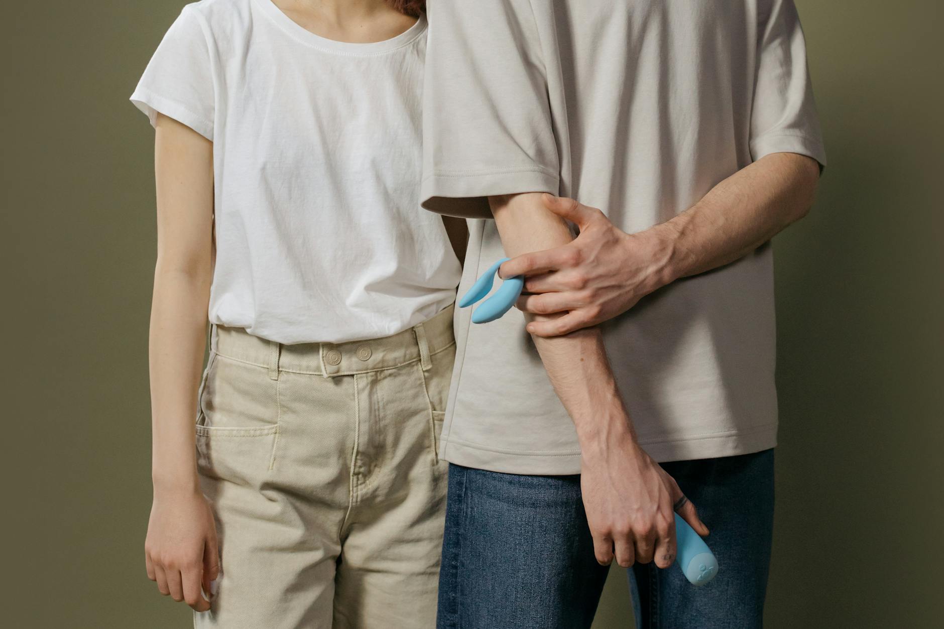 A couple holding a blue vibrator together, symbolizing shared intimacy during pregnancy