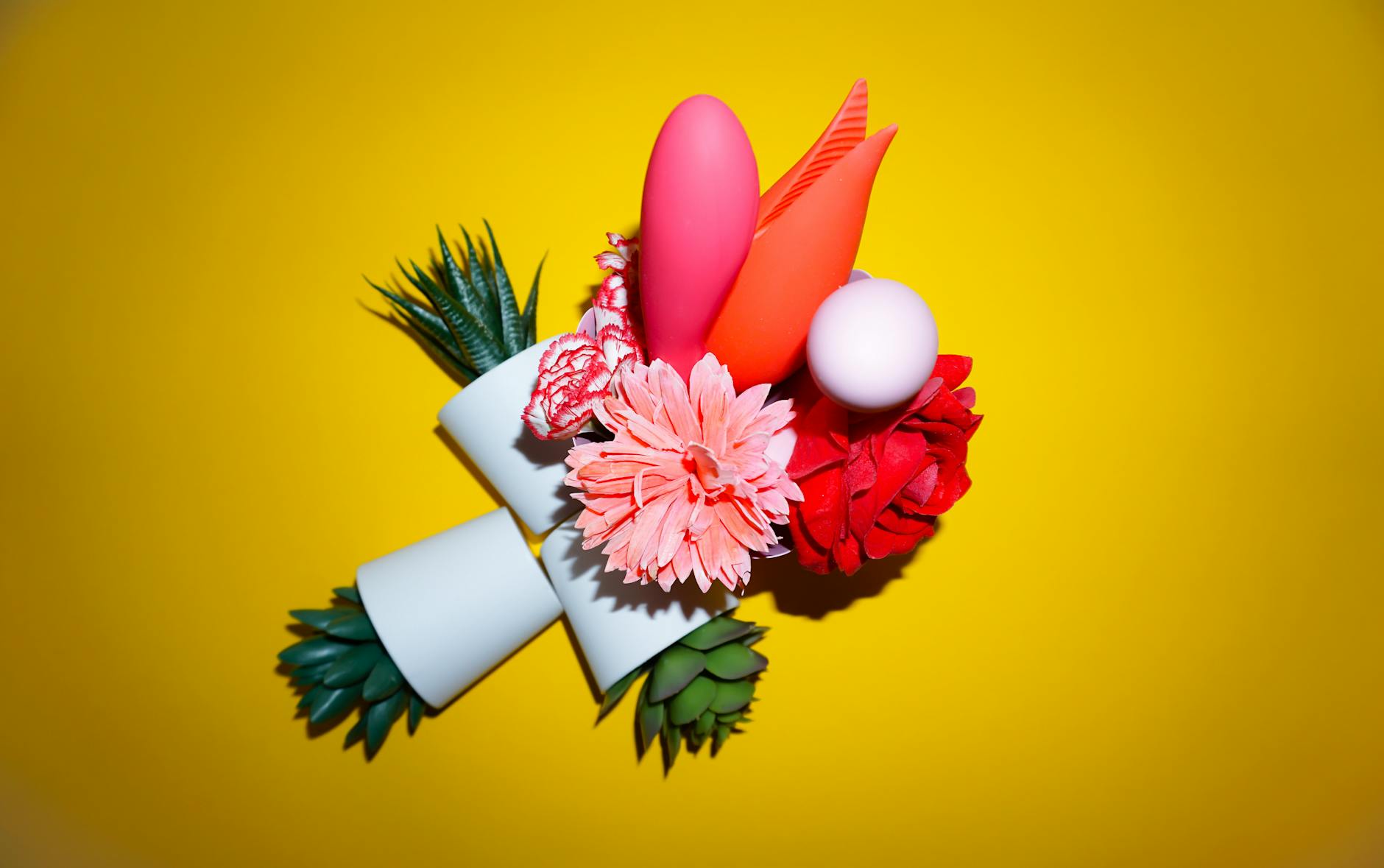 Yellow silicone clitoral vibrator surrounded by peeled bananas on a bright yellow background, representing sensory pleasure